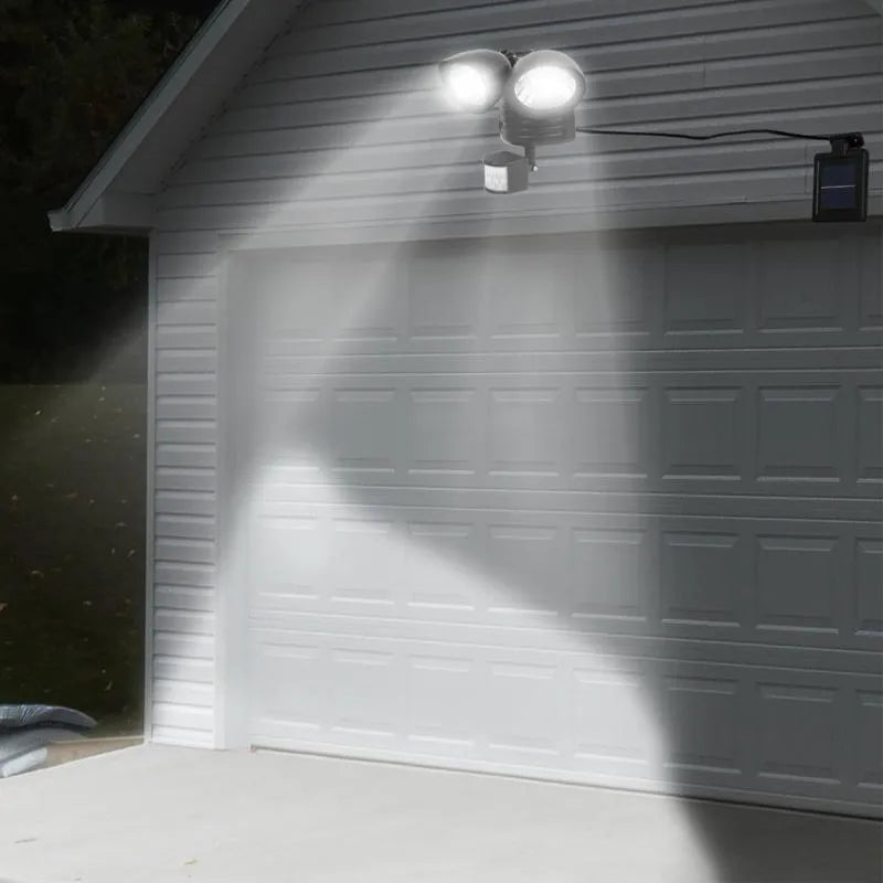 Black dual-head solar security spotlight with motion sensor mounted on exterior wall