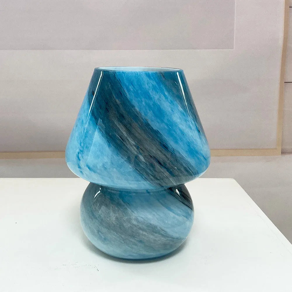 Handmade glass mushroom table lamp in colour finish, 15cm diameter, on a bedside table.