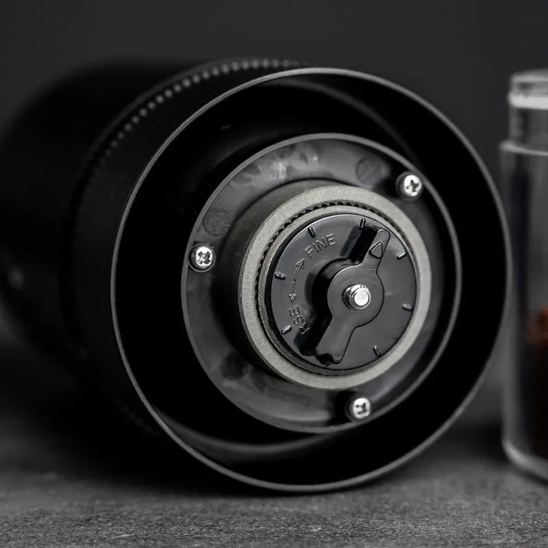 Black portable electric coffee grinder with transparent chamber showing coffee beans, USB-C charging port visible