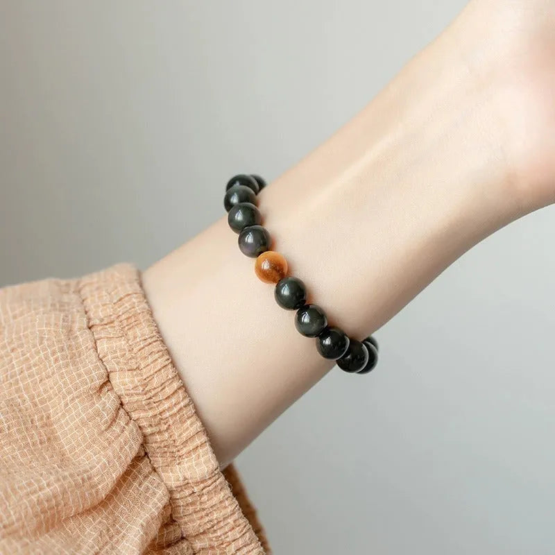 Natural black obsidian geometric bead bracelet on an adjustable string, showing 10mm bead size.