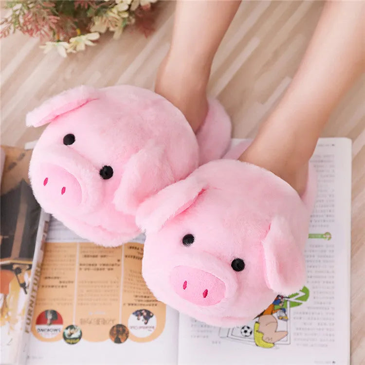 Pink pig-shaped plush floor slippers on a white background.