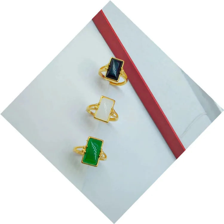 A gold-plated brass ring with an adjustable band and a central green artificial gemstone, in a national style.