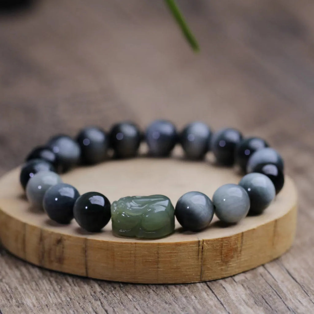 10mm Eagle Eye Stone bead bracelet with a natural Hetian Jade Clear Water Pixiu charm on a black cord.