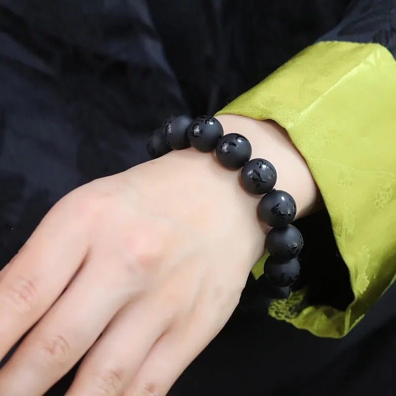 Natural frosted black agate bracelet engraved with a Sanskrit mantra, showing stone-coloured glaze.