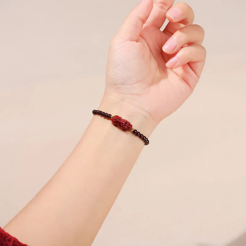 Geometric square garnet bracelet with carved Pixiu and strawberry quartz accents on a purple sand background.