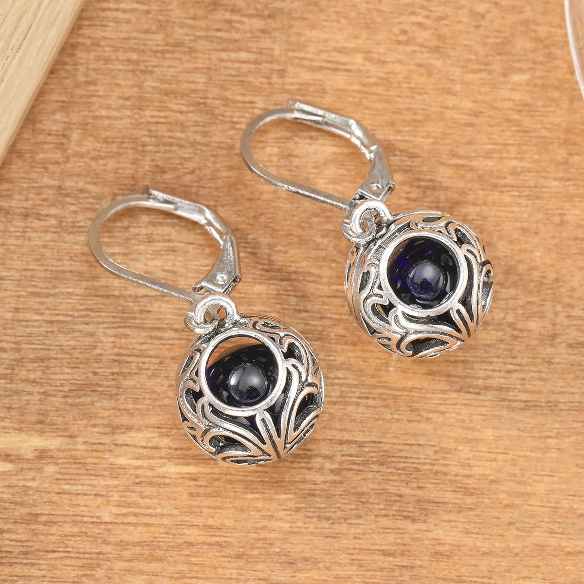 Silver geometric earrings with blue gemstone pendants and hollow engraving details