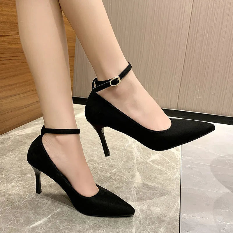 Women's black stiletto heel pump shoes with a buckle strap on the side.