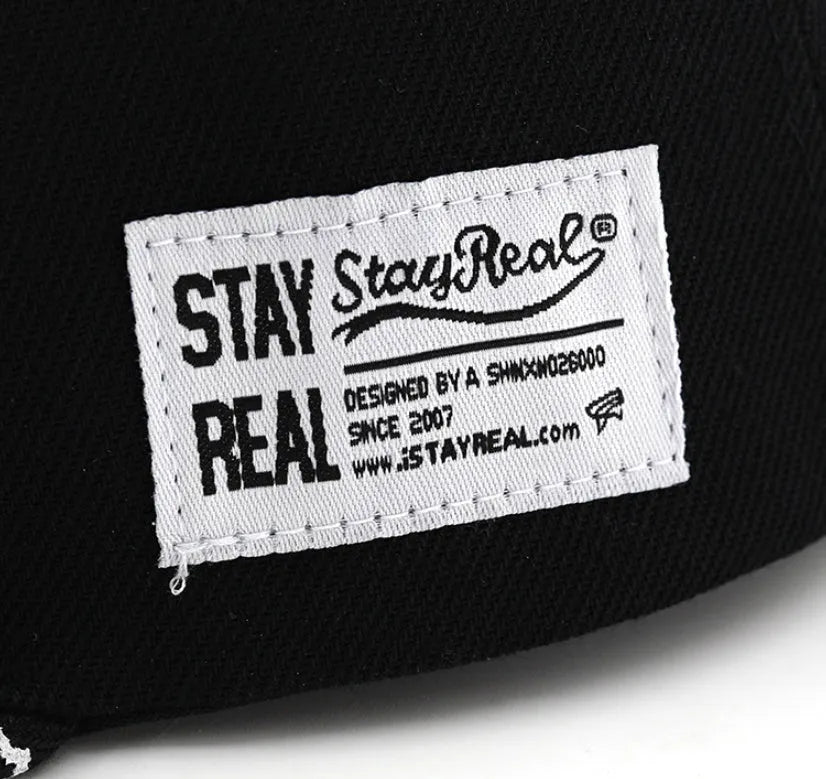 Cotton baseball cap with adjustable strap in black or white, showing embroidered letter detail on the front.