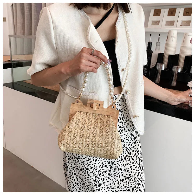 Women's woven straw shoulder bag with pearl chain detail showing horizontal square shape and internal compartments