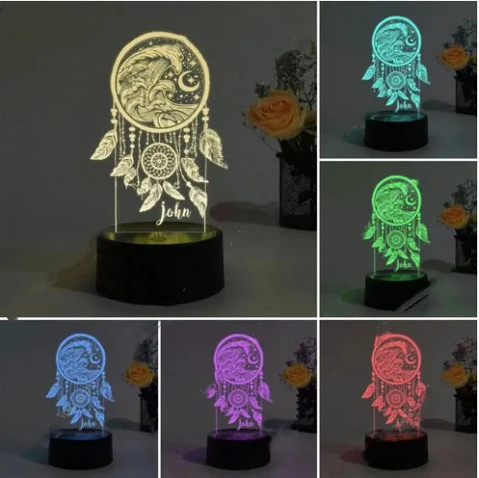Black-based acrylic dream catcher night light with colourful LEDs on a table.