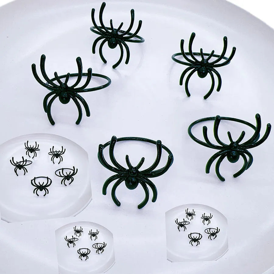 Set of six black metal spider-shaped napkin rings for Halloween table decorations.