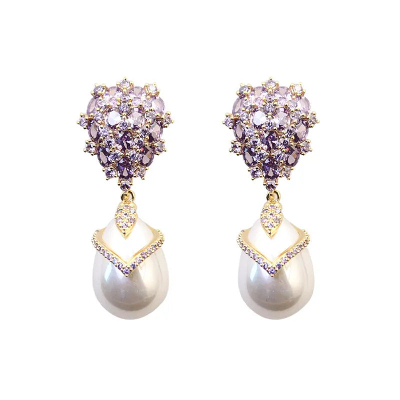 Close-up of a women's drop-shaped earring with inlaid pearl and zircon stones on an 18K gold-plated copper setting.