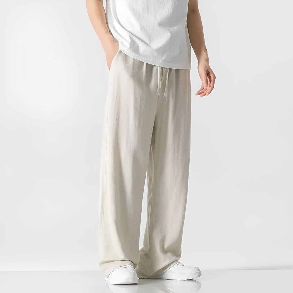 Man wearing beige straight-leg cropped linen-style trousers with a drawstring waist.
