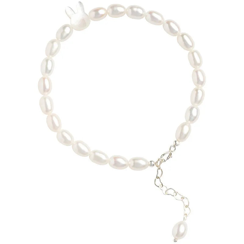 White pearl and silver rabbit charm bracelet on a stretched elastic string showing its adjustable fit.