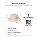 Beige and grey wine bottle-shaped camping lantern with USB-C port on a wooden table.
