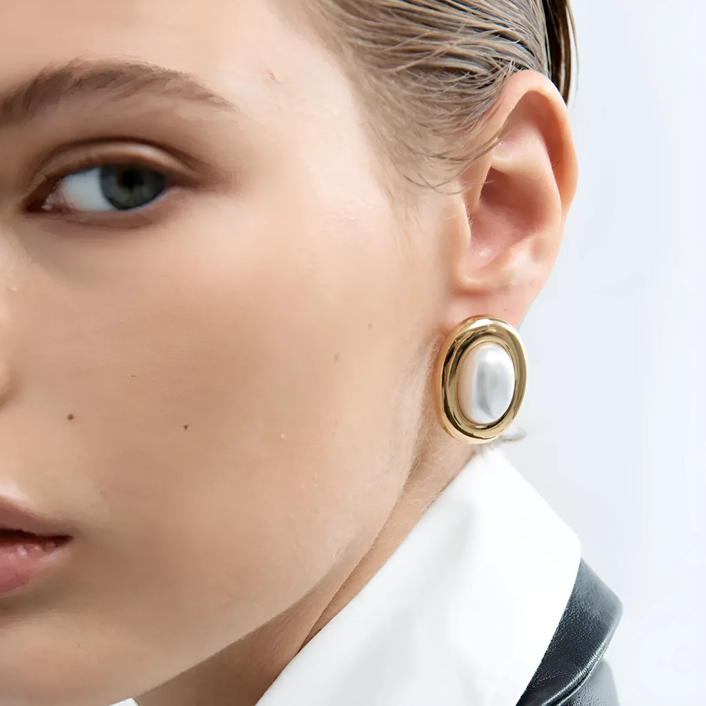 A pair of stainless steel stud earrings with a small vintage-style pearl drop and a non-fade electroplated finish.