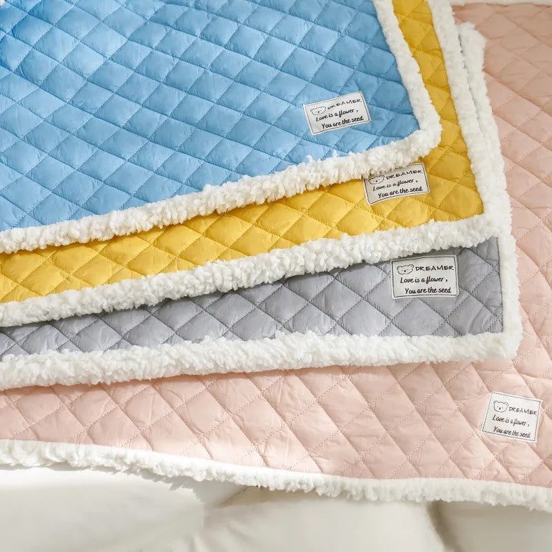 Blue quilted cloth pet blanket for cats lying flat, showing its rectangular shape and textured surface.