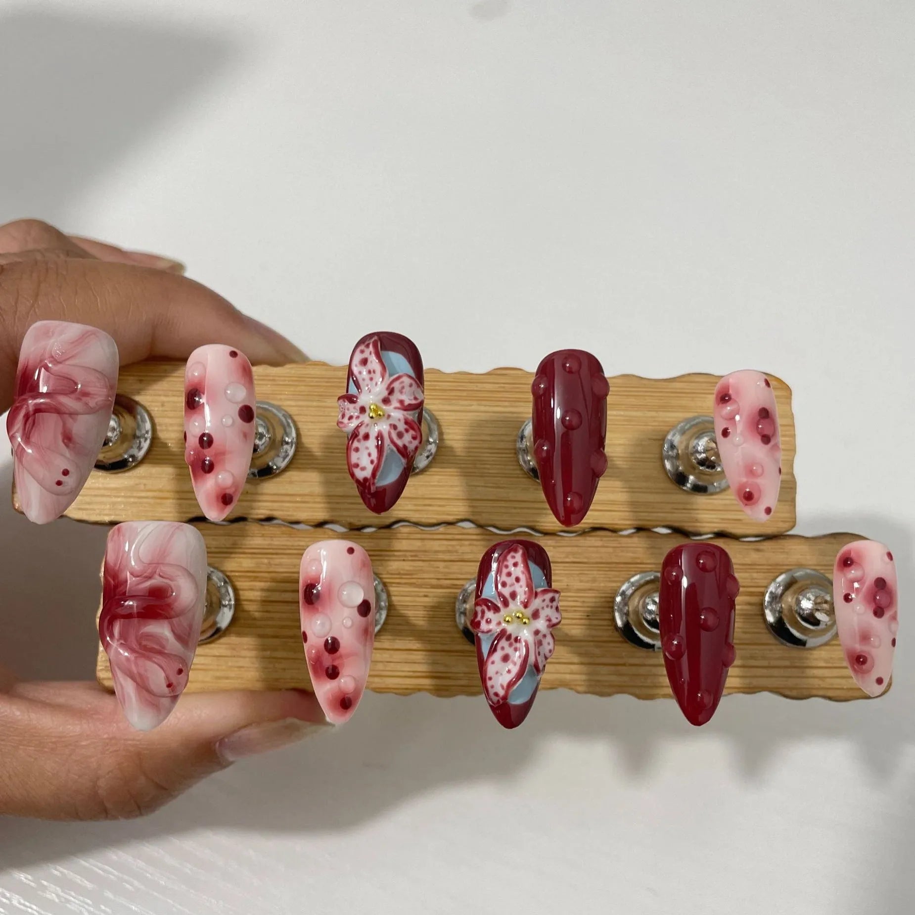Set of almond-coloured artificial nails with hand-painted rose and 3D carved butterfly designs, showing short and medium lengths.