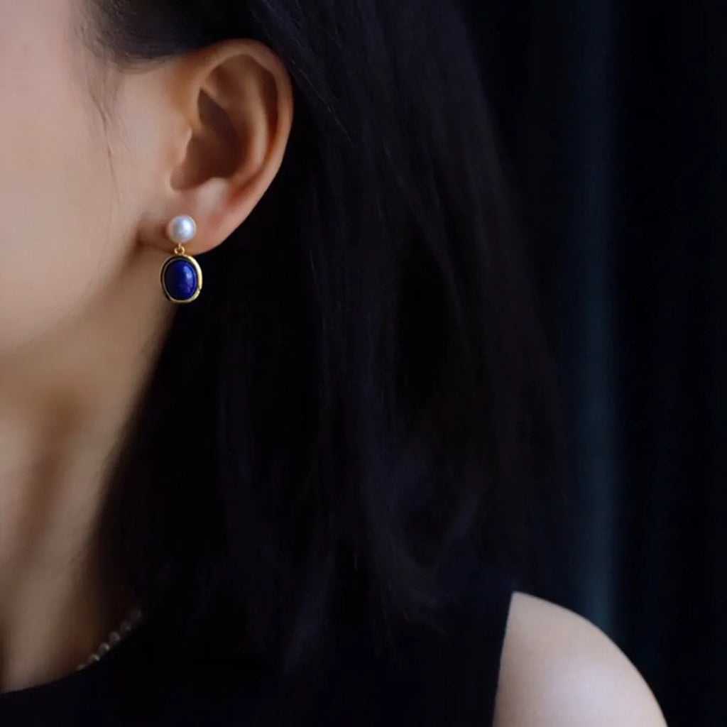 A pair of simple sterling silver drop earrings with blue lapis lazuli pearls and an auspicious pattern.