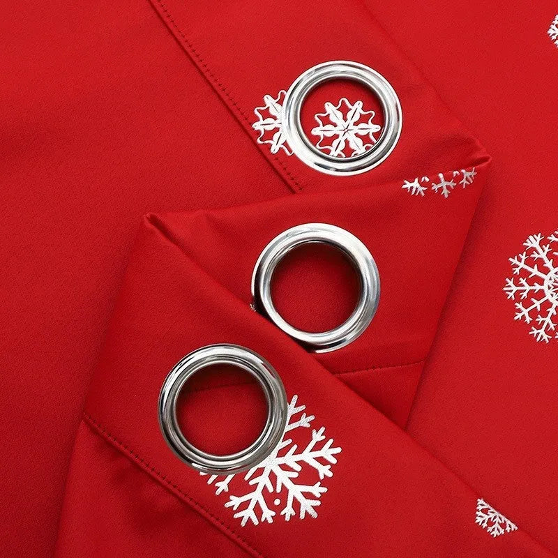 Red snowflake pattern shade cloth curtain with iron hoops hanging on a rod against a window.