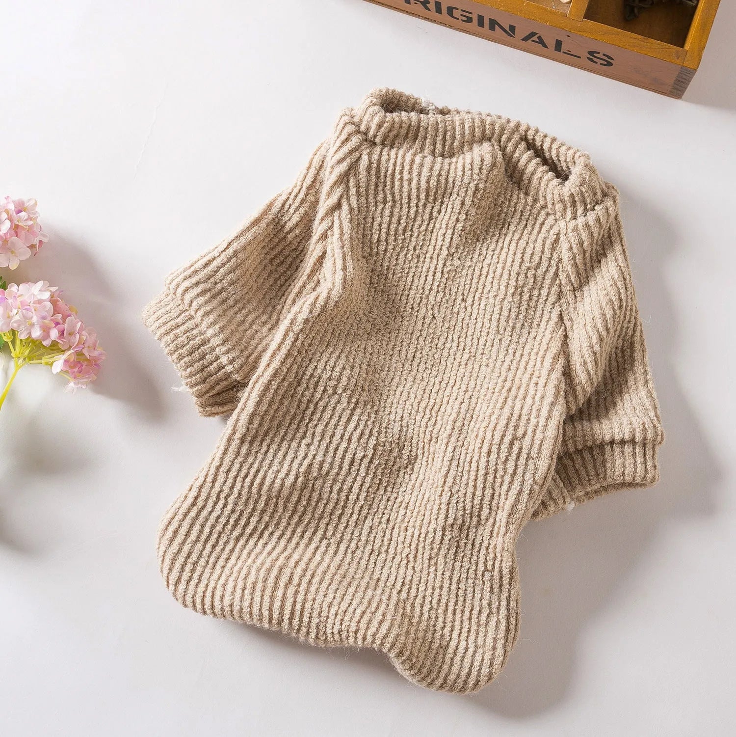 A brown knitted pullover sweater for a small dog on a mannequin.