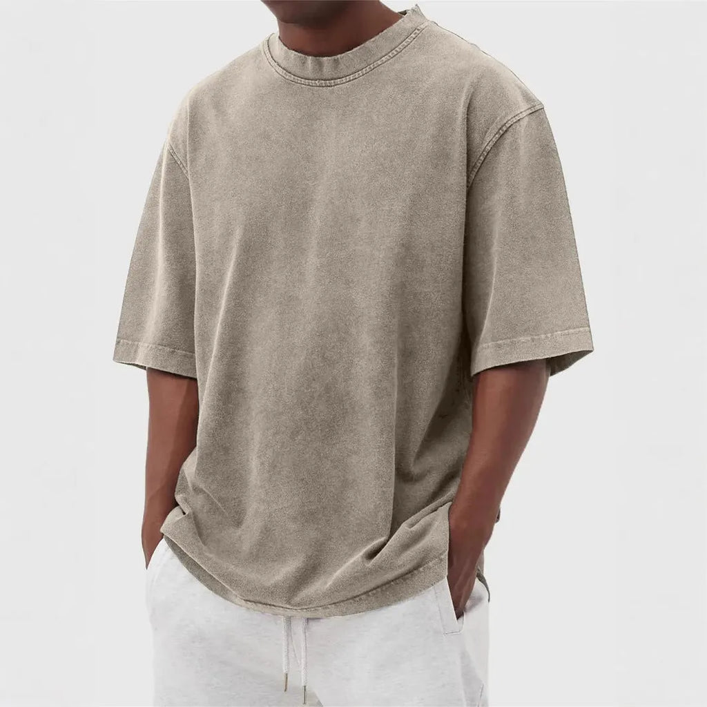Man wearing a loose fit stone washed distressed t-shirt in a solid colour, showing short sleeves and casual styling.