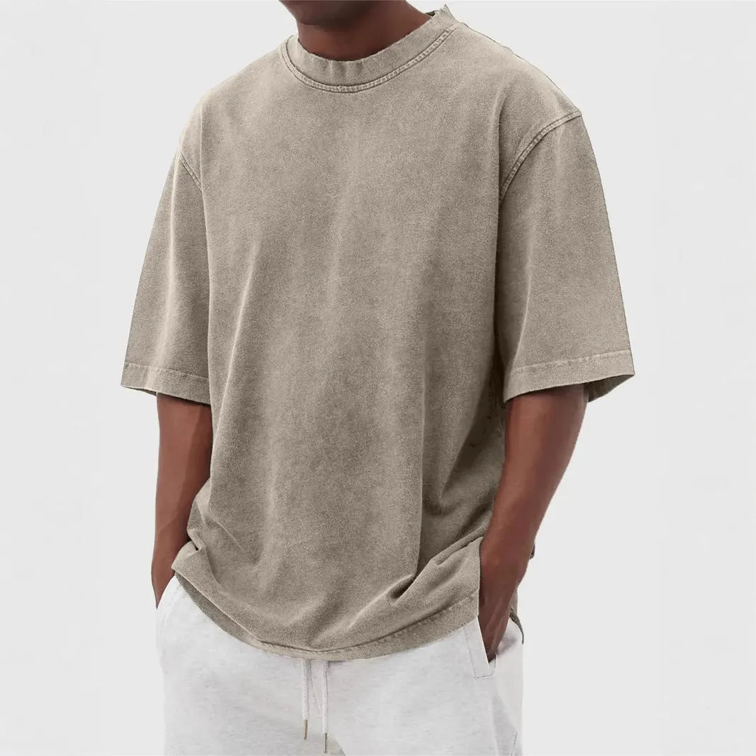 Man wearing a loose fit stone washed distressed t-shirt in a solid colour, showing short sleeves and casual styling.