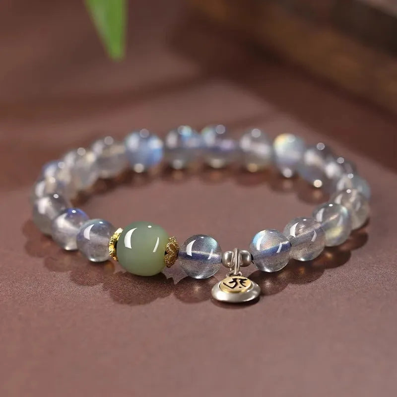Close-up of a women's bracelet with 8mm moonstone beads and an electroplated Kwan-yin mouse charm.
