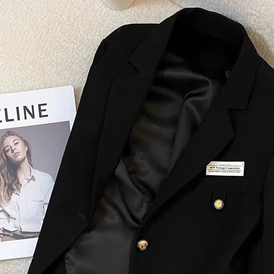 A women's loose-fit short black suit coat with long sleeves and front pockets.
