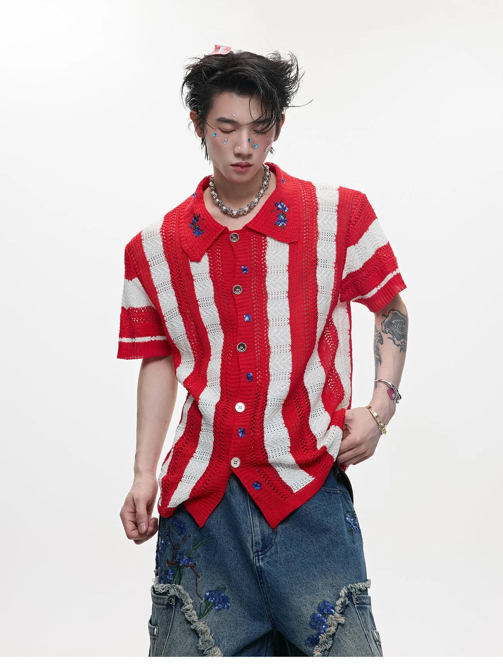 Man wearing a red and black patchwork striped knitted short sleeve shirt with a loose fit.