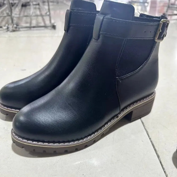 Black round toe ankle boot with a silver belt buckle decoration on the side.