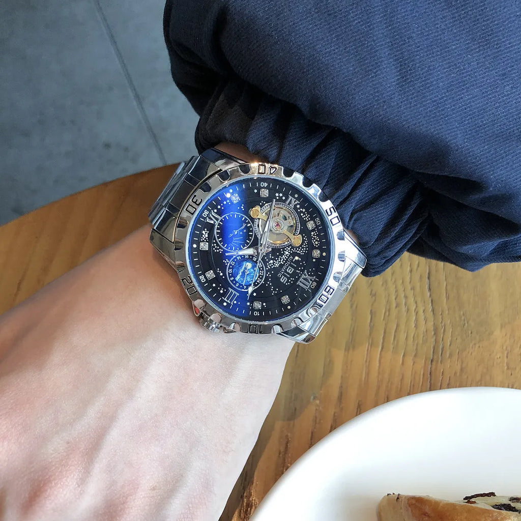 Men's silver automatic watch with black leather strap and transparent case back.