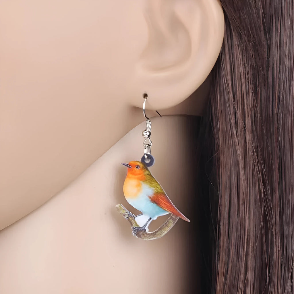 A pair of blue titmouse pendant earrings made from printed acrylic with a geometric, animal-inspired design.