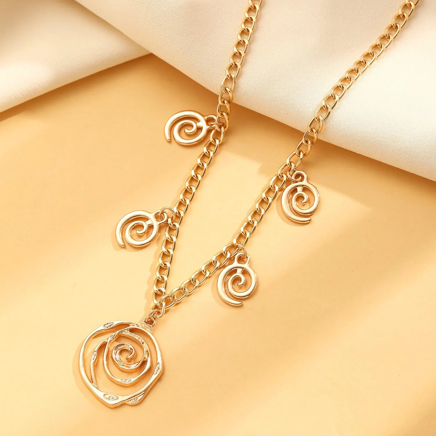 Geometric spiral donut jewellery set showing necklace, bracelet, and earrings in gold electroplated finish