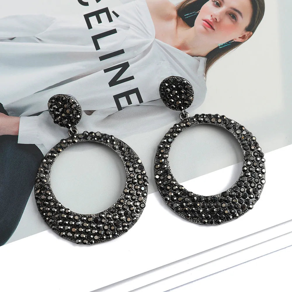A pair of large round pendant earrings with colourful diamond-like accents on a metal alloy base, cartoon style.