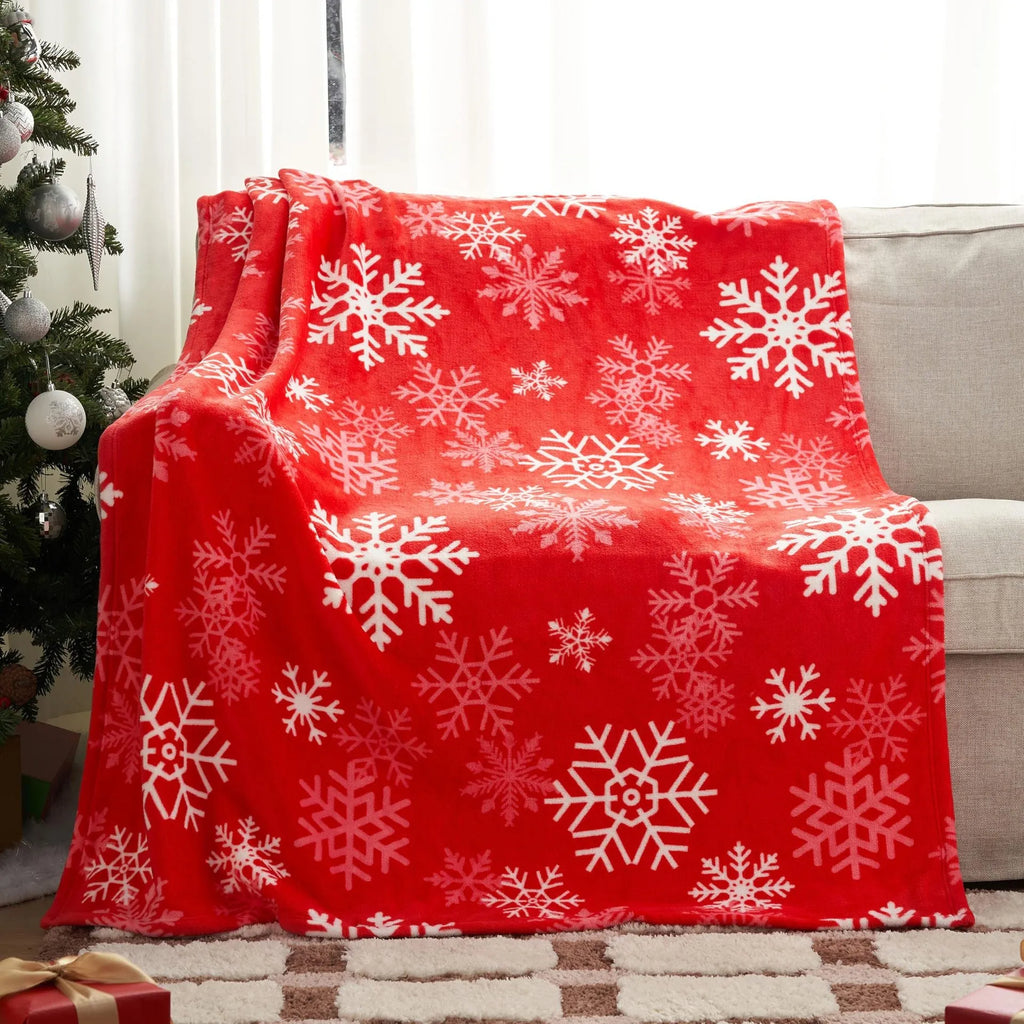 Soft red polyester flannel Christmas blanket draped over a sofa, showing its plush texture and generous size.