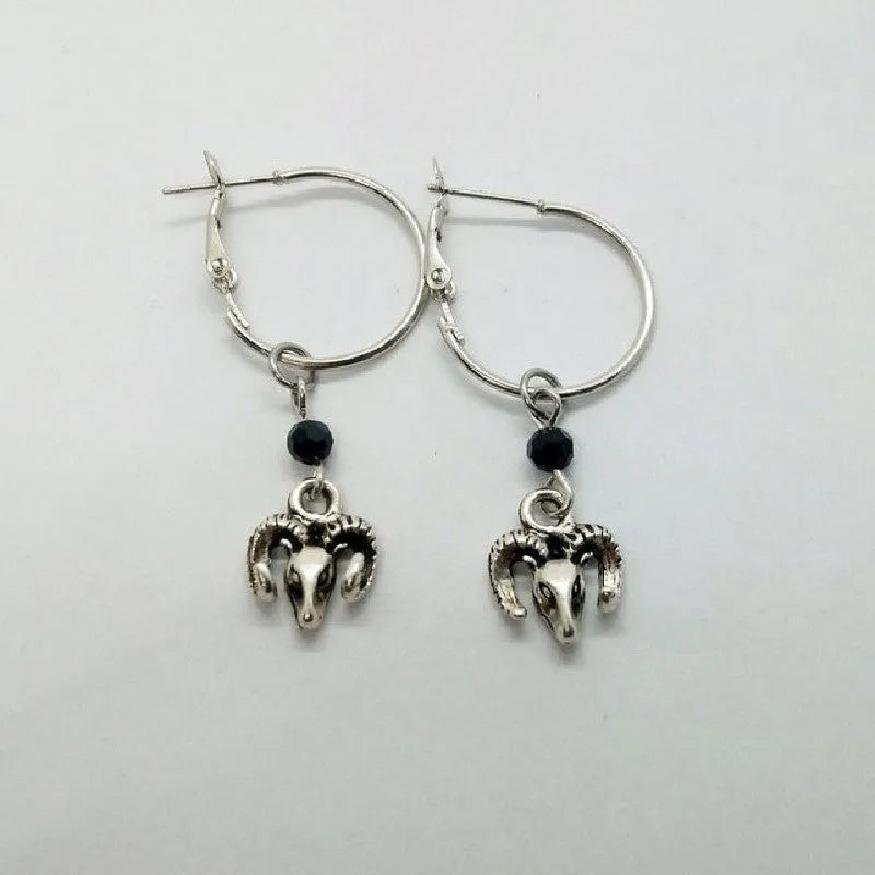 A pair of silver-coloured alloy round ring hoop earrings on a plain background.