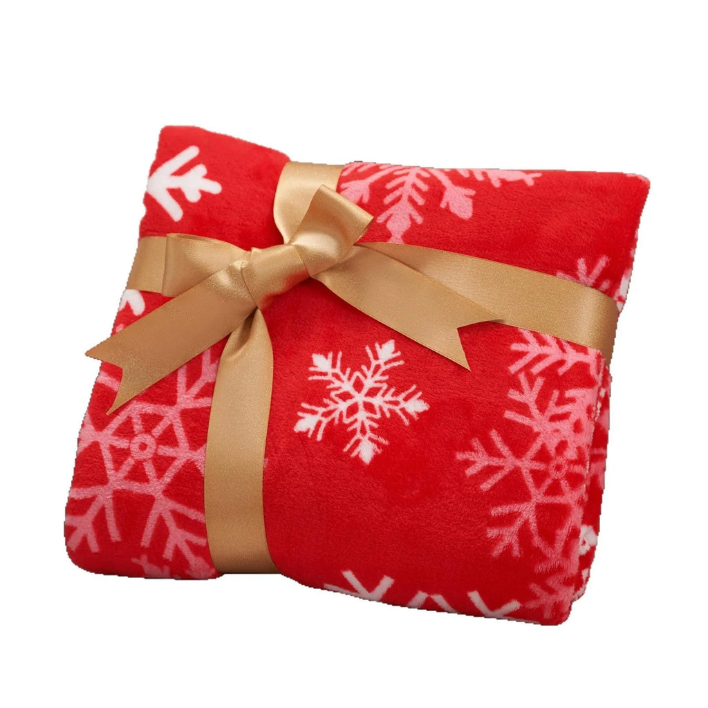 Soft red polyester flannel Christmas blanket draped over a sofa, showing its plush texture and generous size.