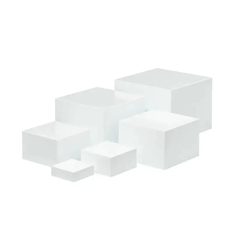 Set of six white plastic cube dessert display stands arranged on a tabletop.