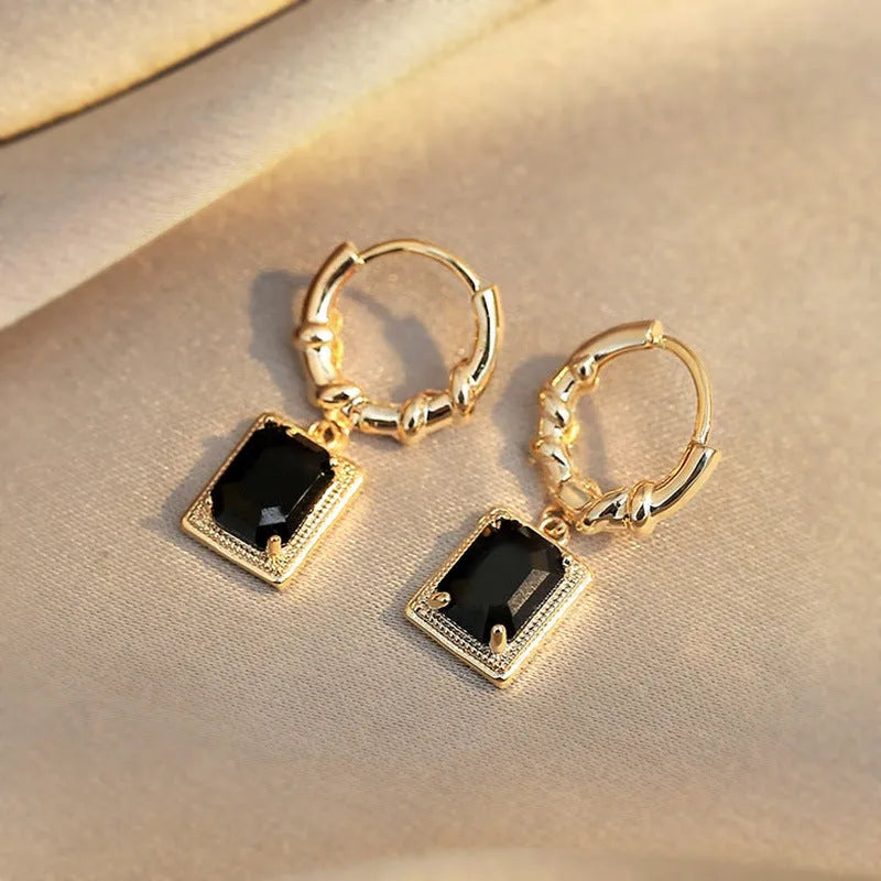 Close-up of black geometric quadrilateral stud earrings with zircon stones on a French court wire.