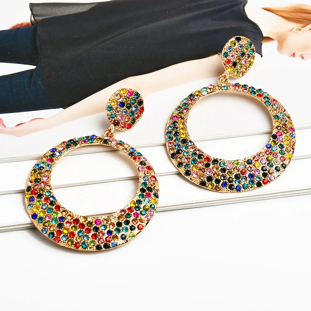 A pair of large round pendant earrings with colourful diamond-like accents on a metal alloy base, cartoon style.