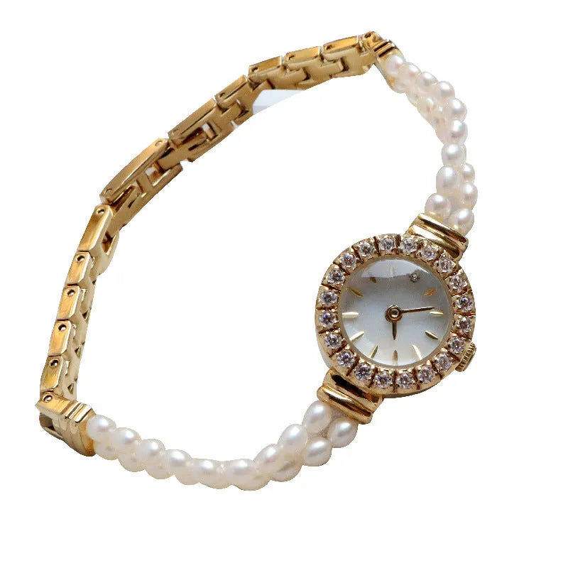 Light gold women's bracelet watch with freshwater pearls, round 18mm dial, and stainless steel strap.