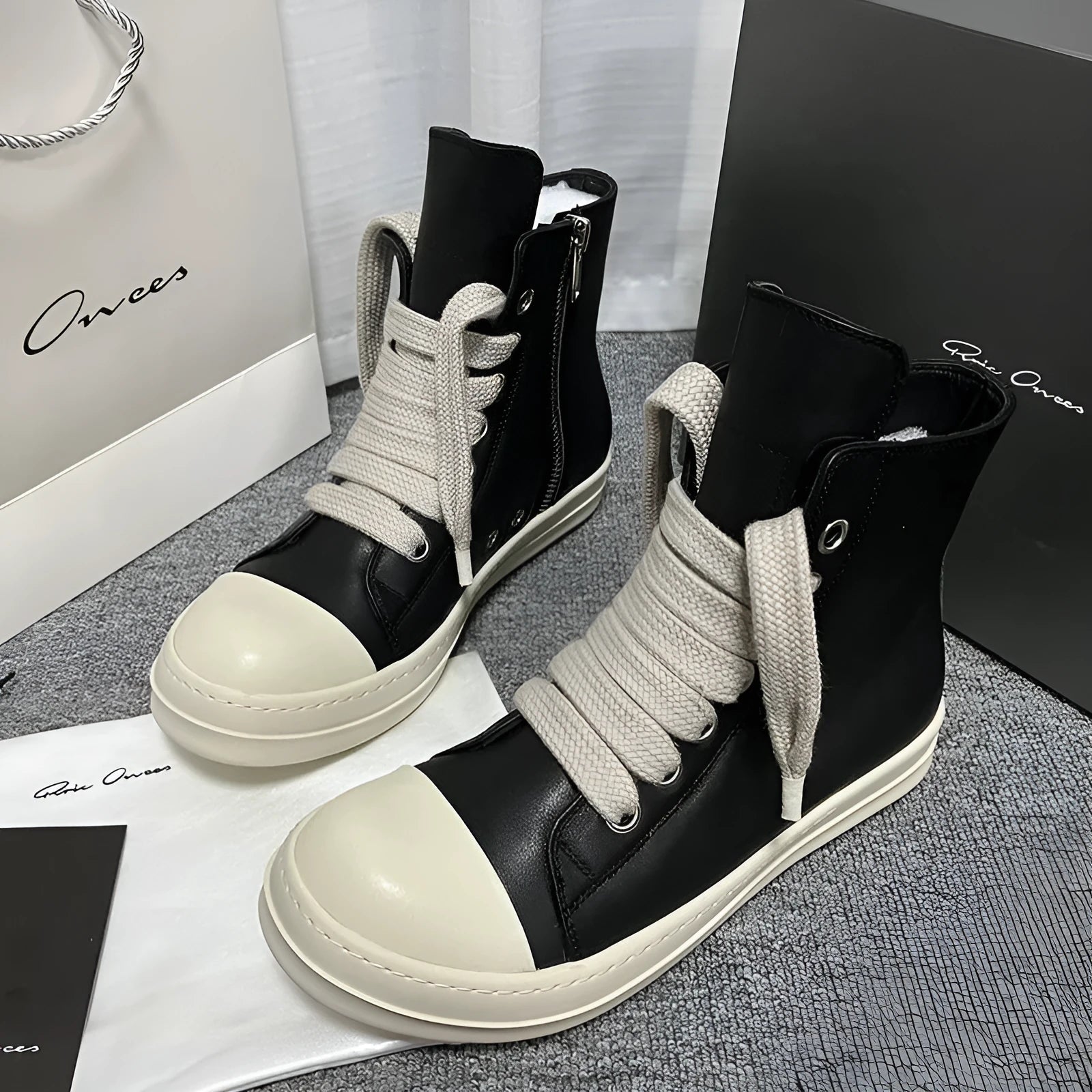 Men's and women's high-top leather sneakers in black with a side zipper and round toe on a rubber sole.