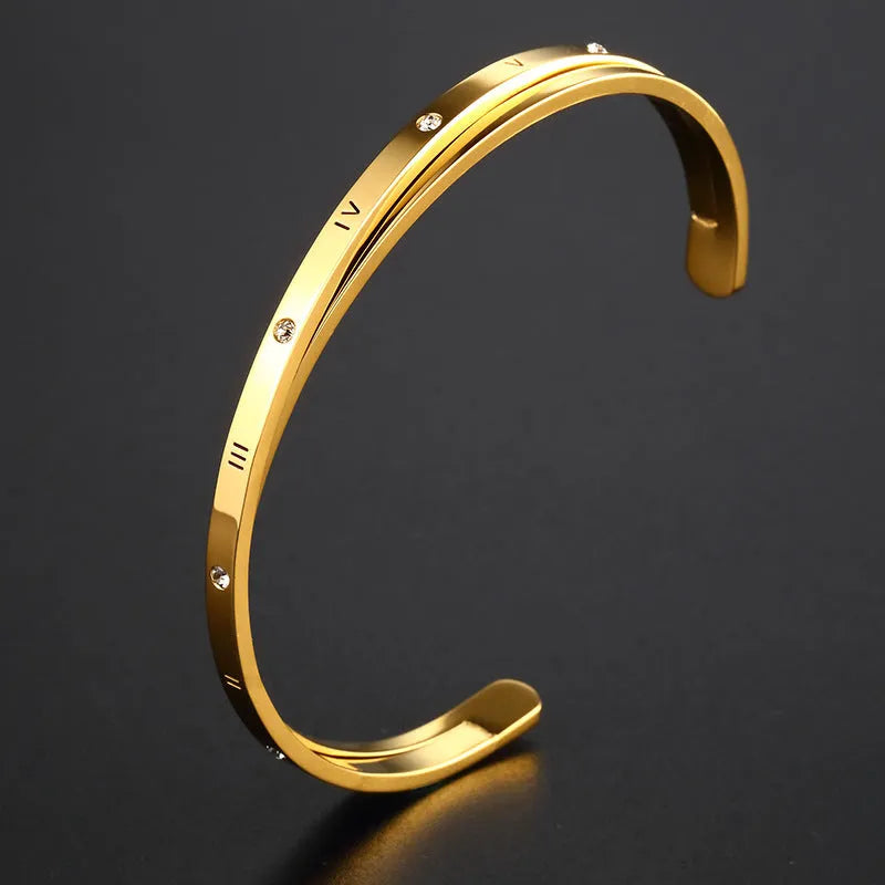 Open-ended stainless steel bracelet with zircon inlays in a love theme, shown in gold colour.