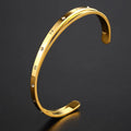 Open-ended stainless steel bracelet with zircon inlays in a love theme, shown in gold colour.