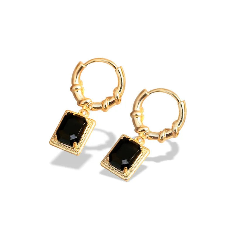 Close-up of black geometric quadrilateral stud earrings with zircon stones on a French court wire.