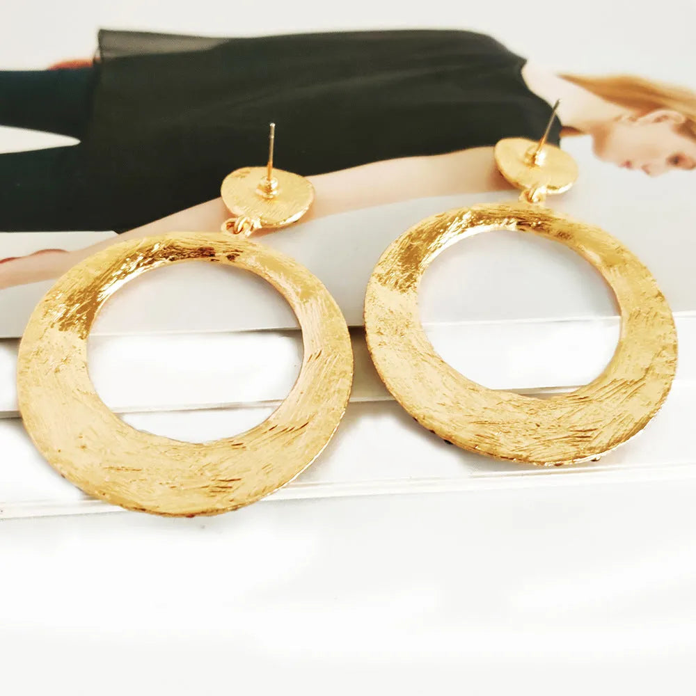 A pair of large round pendant earrings with colourful diamond-like accents on a metal alloy base, cartoon style.
