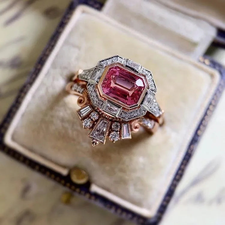 Rose gold coloured alloy women's ring with a geometric retro design and ruby-style details on a white background.