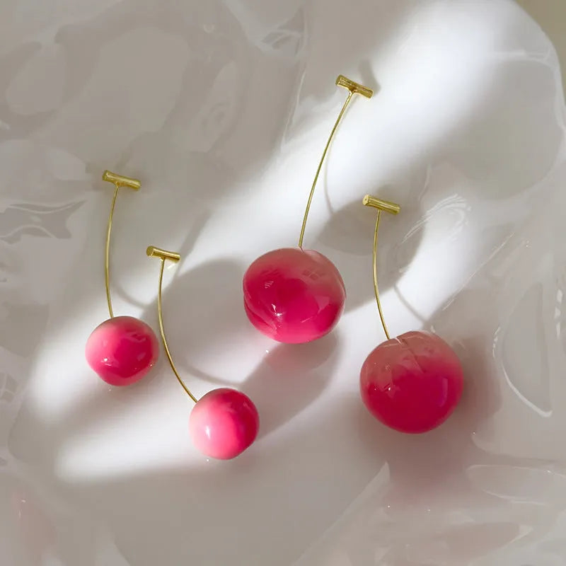 A pair of peach-shaped acrylic earrings on copper posts, shown in small and large size options.