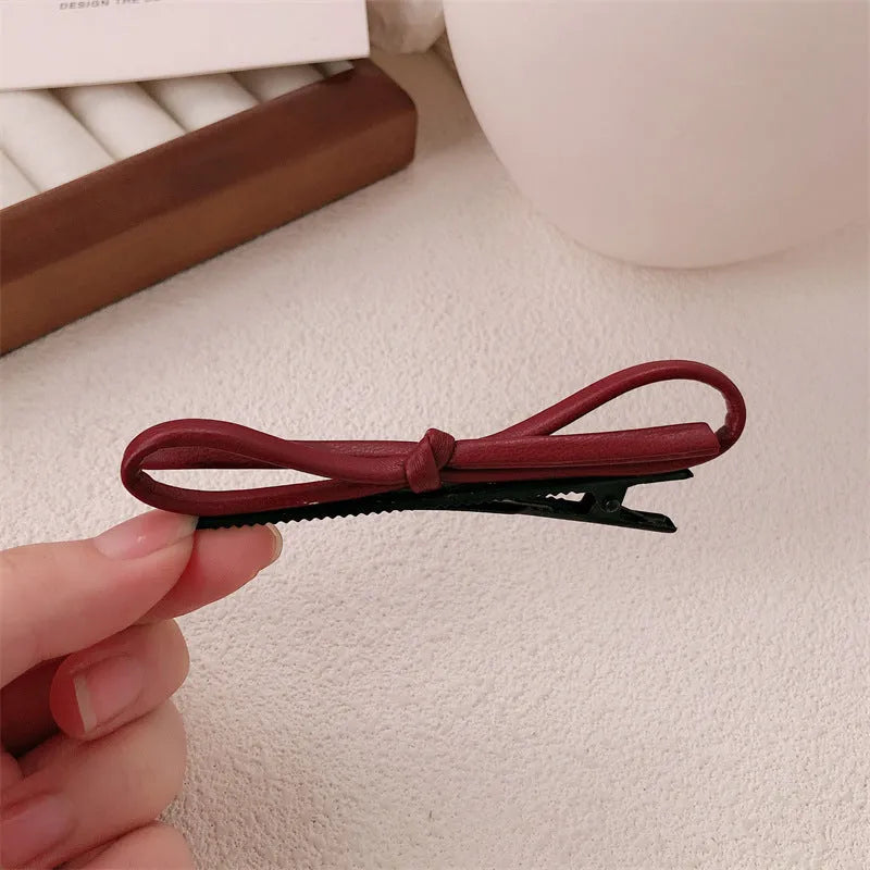 Wine red leather bow hair barrette on a white background.